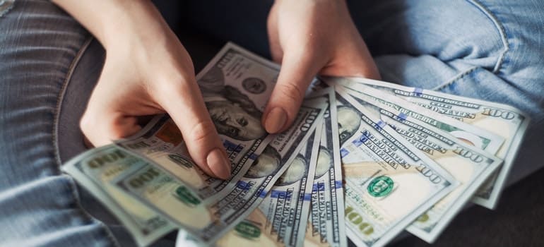 woman counting dollar bills and thinking of pros and cons of moving to Manhattan