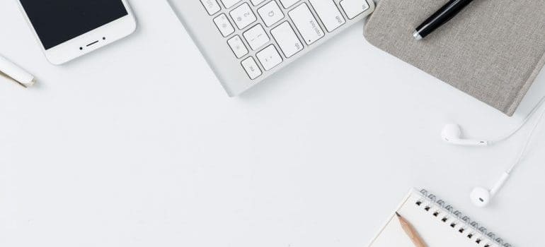 Keyboard, phone, pen, notebook on the table.