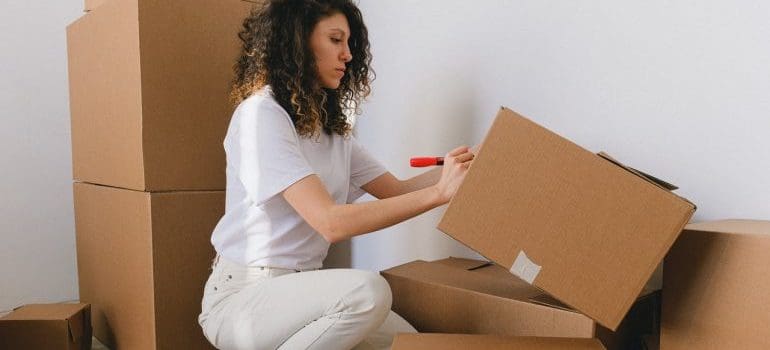 Girl labeling a box for the move with a marker.