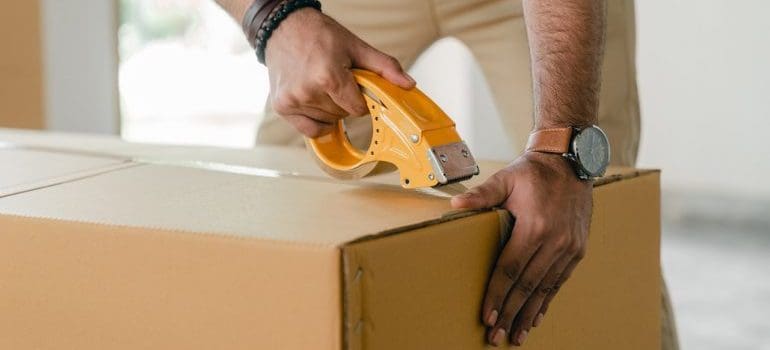 Person securing the box with a scotch tape.