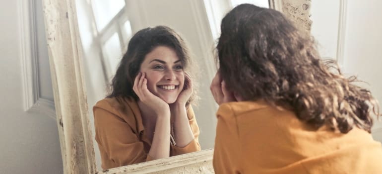 A woman smiling to herself in the mirror