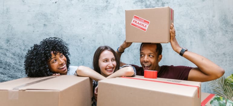 people smiling and holding packing supplies