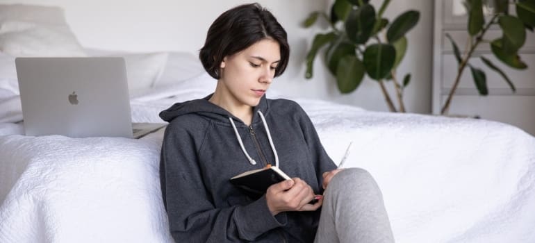 A woman reading her notes in front of a bed