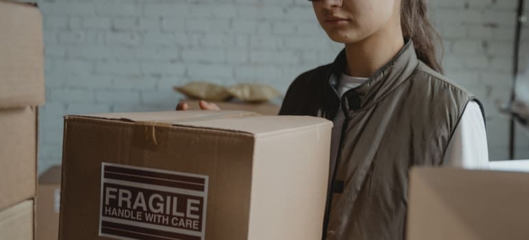 Woman in brown vest wearing a cardboard box.