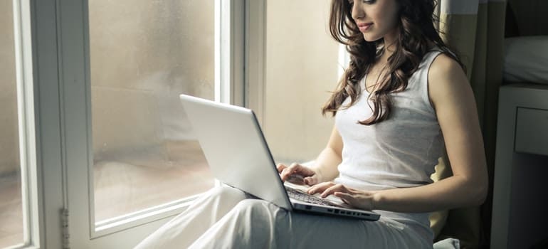 a woman reading on her laptop where to Relocate to After New York City