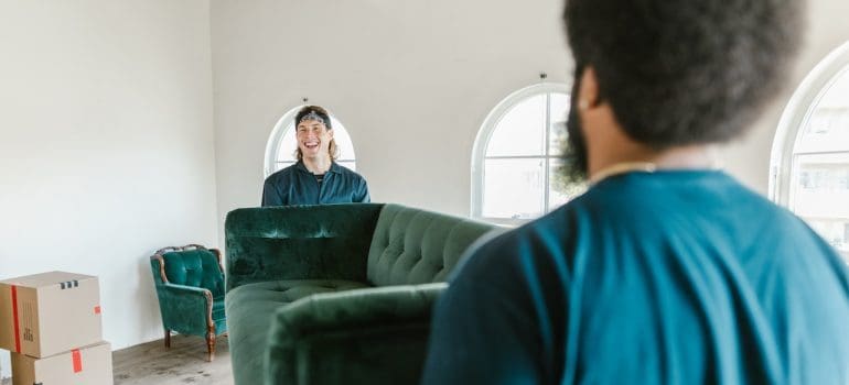 Two men from a moving company carrying a couch.