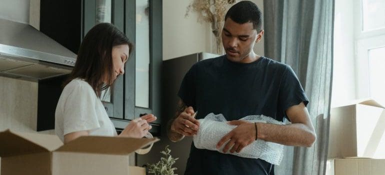 A man and a woman packing for their Manhattan relocation, to keep the relocation costs down.