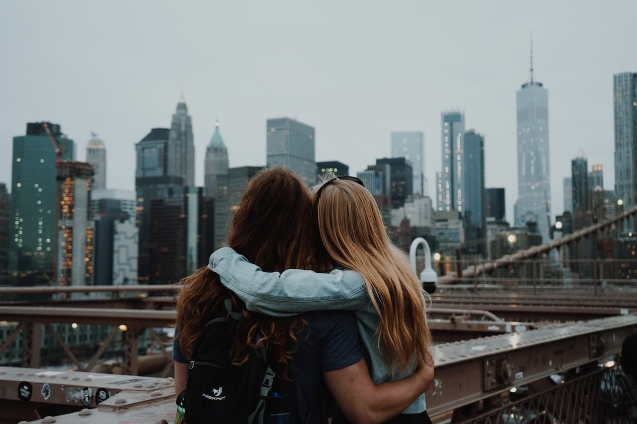Two girls hugging and looking towards New York City.