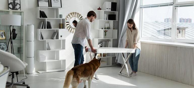 a couple moving a table, getting ready for office moving in Queens