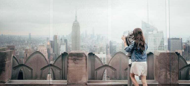 woman in blue denim jacket is looking at the city