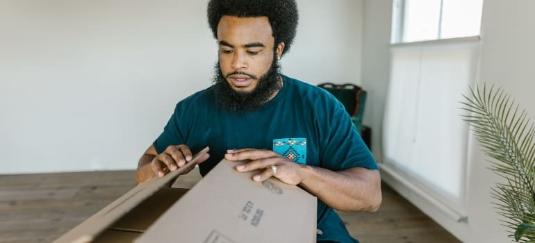 A man unpacking a box and thinking of benefits of professional packing services
