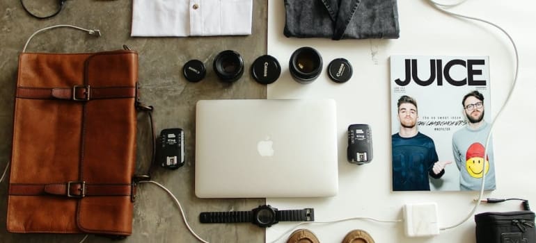 a bag next to a laptop next to a magazine with many other essentials